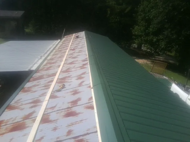 Old rusted panels beside newly installed green metal roofing — Wind Damage Roof Repair by Roofing Brothers in Sharon